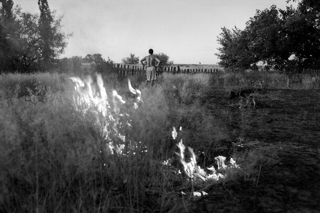 «Истории, рассказанные спиной». Фотовыставка о том, как тело говорит о человеке, Хозяин жжет траву на участке. Хутор Сеньшин, Обливский район, Ростовская область, Россия. Июль 2010 — Михаил Масленников (Творческий союз «НОГА») — discours.io