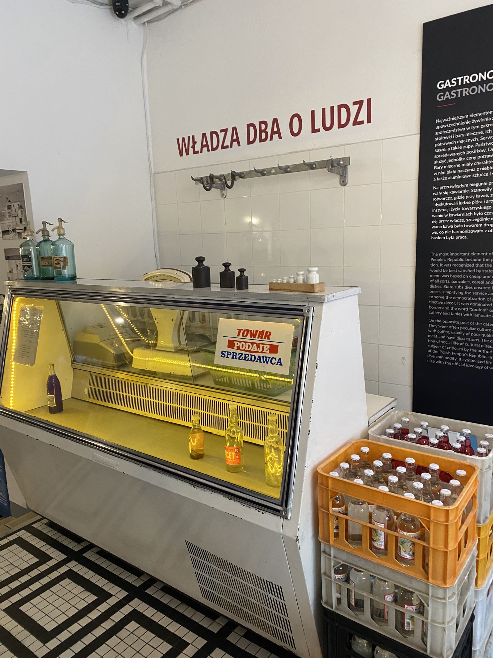 Ассортимент продуктового магазина в&nbsp;1970-е гг. Надпись по-польски на&nbsp;стене: «Власть заботится о&nbsp;людях». Экспозиция музея жизни в&nbsp;ПНР, Варшава. Фото автора.