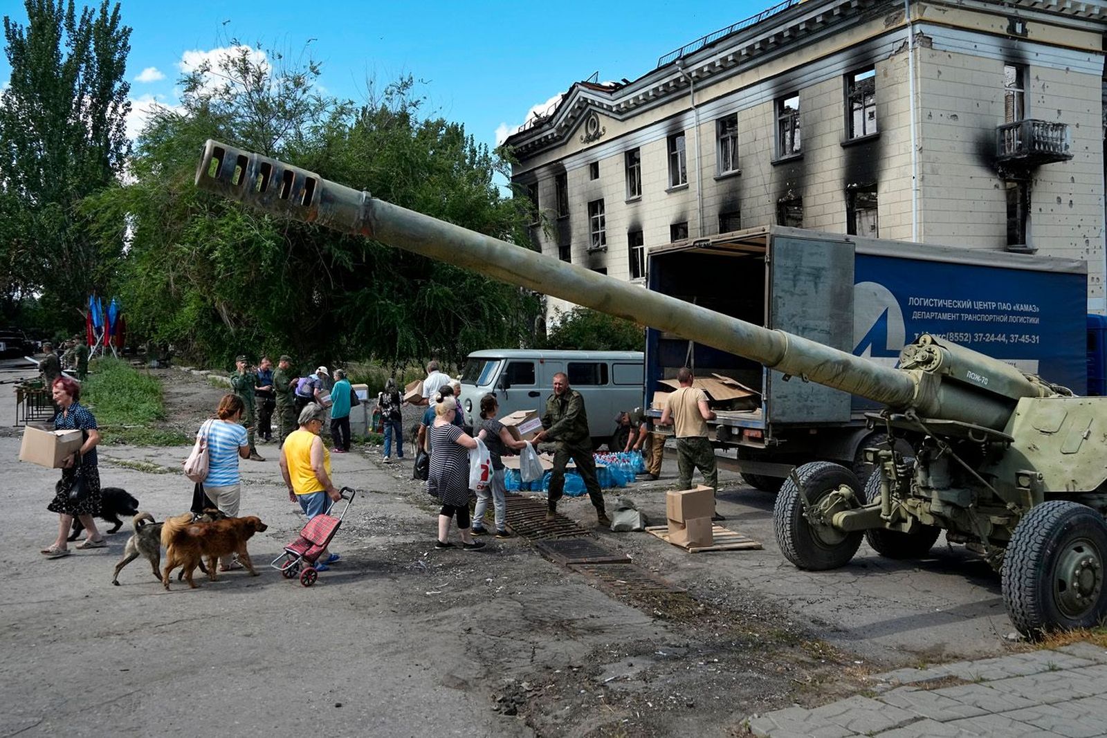 Жители Лисичанска получают гуманитарную помощь рядом с выставкой трофейных украинских танков и другого вооружения. По состоянию на 12 июля город находится под контролем самопровозглашенной ЛНР. 12 июля / AP / Scanpix / LETA / Meduza