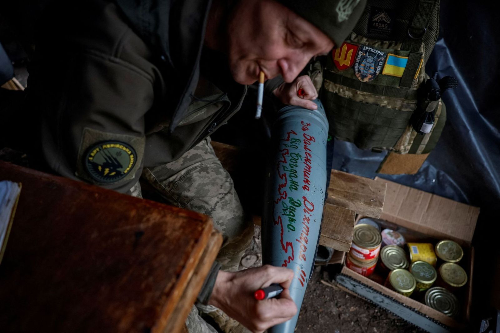 45-летний командир артиллерийского расчета украинской армии наносит имена погибших товарищей на снаряд перед его запуском. 6 ноября / Alina Smutko / Reuters 