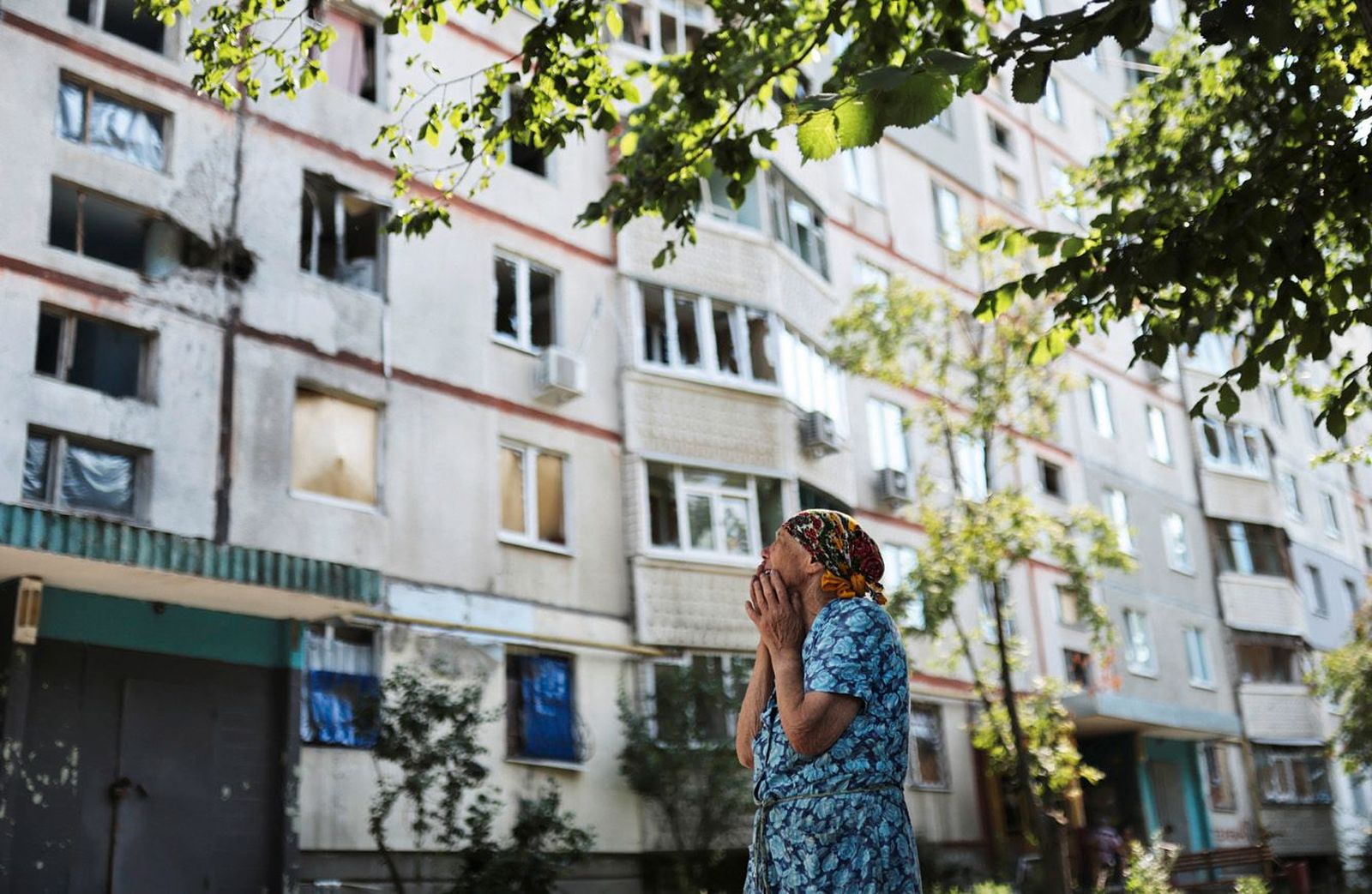 Жительница Харькова смотрит на поврежденный обстрелами жилой дом. 15 июля российские ракеты попали по территории учебных заведений в двух районах города, сообщал глава областной администрации Олег Синегубов. По его словам, рядом с местами, куда попал