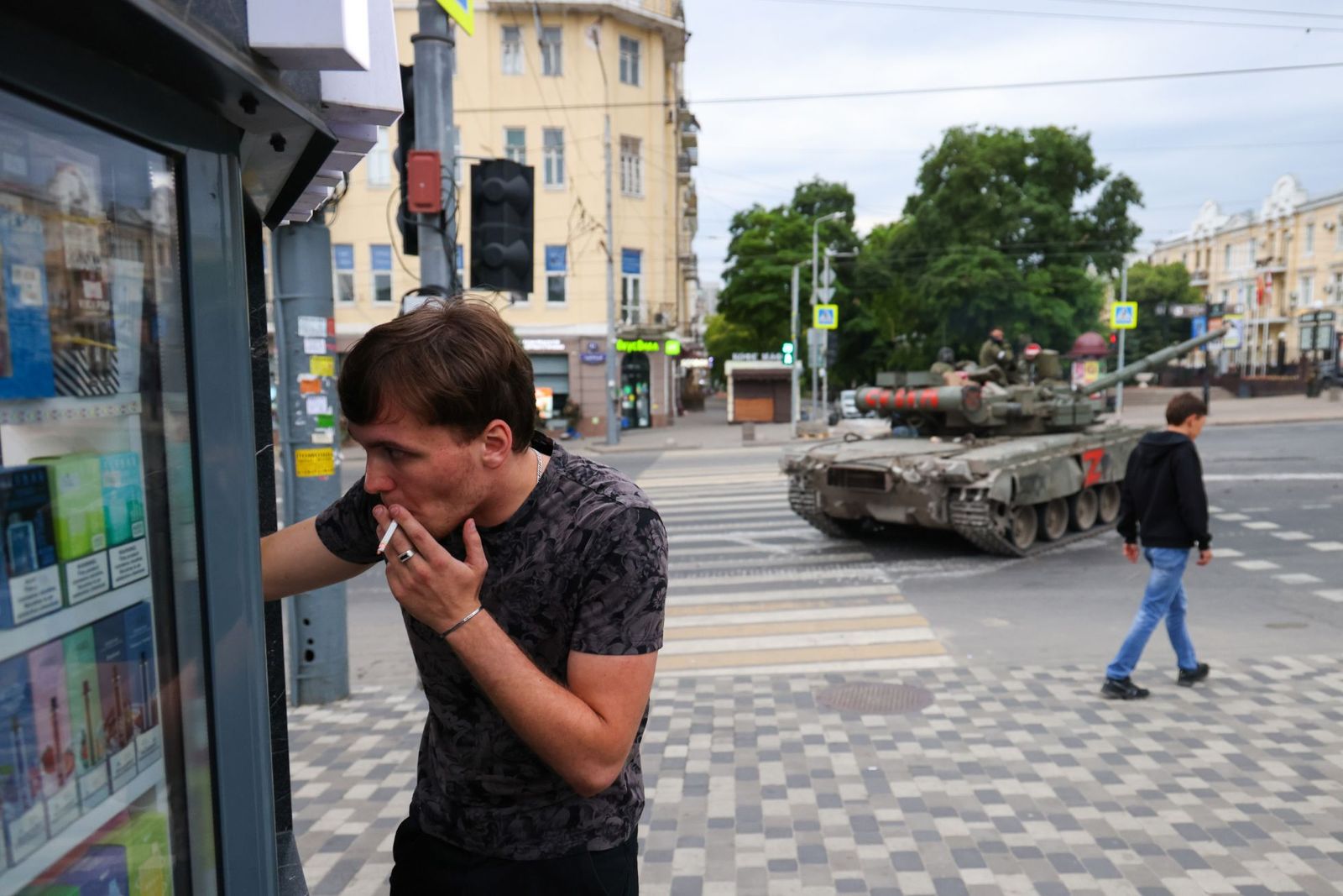 Мужчина стоит у табачного ларька в Ростове-на-Дону, пока по улицам города проходят танки ЧВК Вагнера в ходе военного мятежа. Накануне 23 июня Евгений Пригожин опубликовал видео якобы удара Минобороны по полевым лагерям своей частной армии, после чего