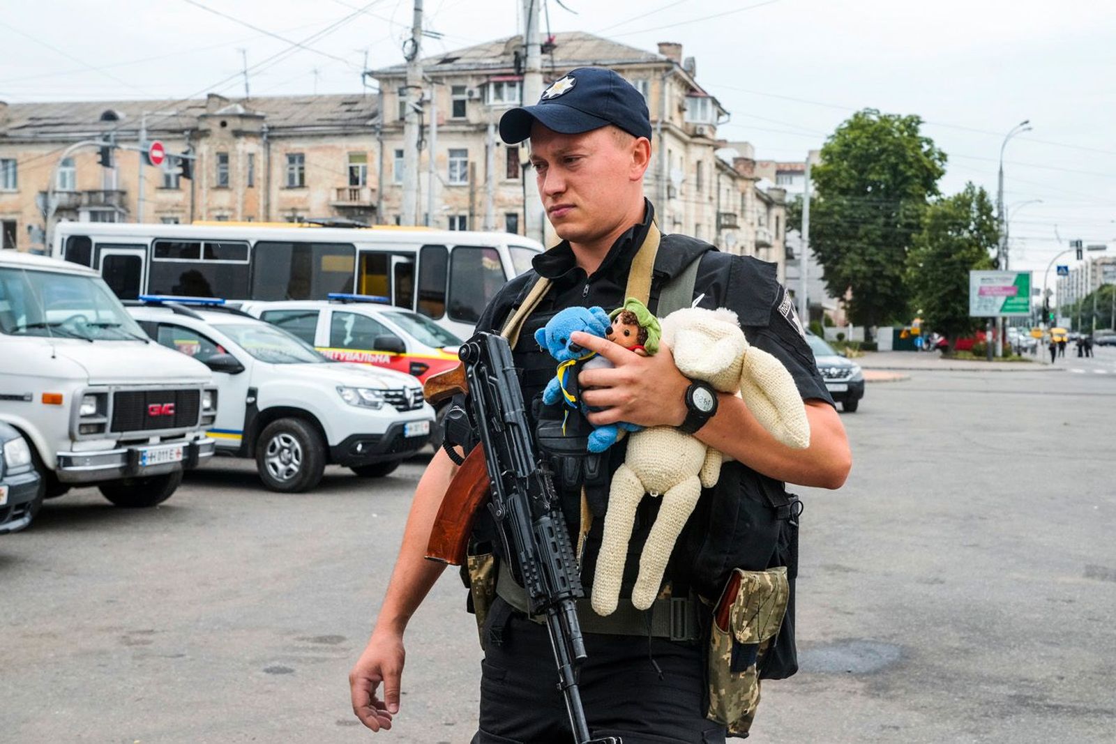 Украинский полицейский несет детские игрушки к месту российского ракетного удара, где создан стихийный мемориал. С утра 15 июля винничане несут к нему игрушки и цветы. В результате обстрела погибли трое детей четырех, семи и восьми лет, четверо детей