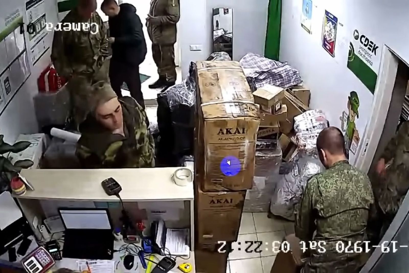 Кадр с записи видеокамеры, на котором российские военные в белорусском отделении СДЭК упаковывают посылки для отправки в Россию. Военнослужащие приносили в курьерское отделение электросамокат, кондиционеры, аккумуляторы. На видеозаписи виден пакет из