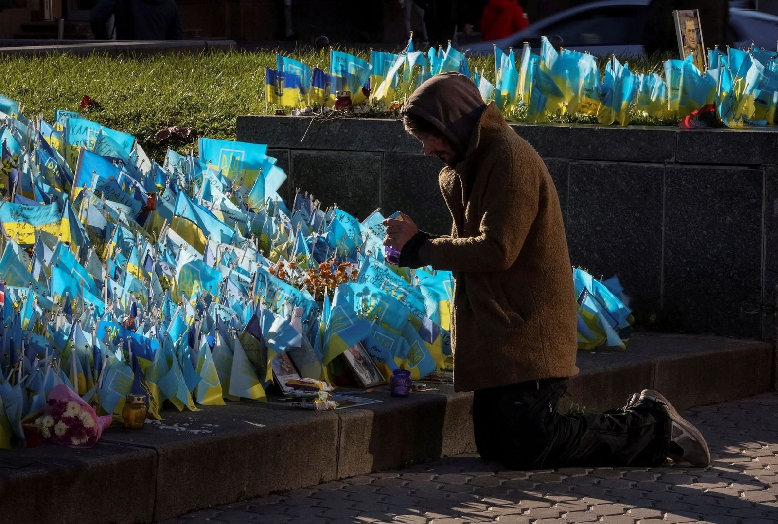 Мужчина зажигает лампадку на импровизированном мемориале с украинскими флагами и именами погибших военнослужащих на площади Независимости в Киеве. 7 ноября / Gleb Garanich / Reuters