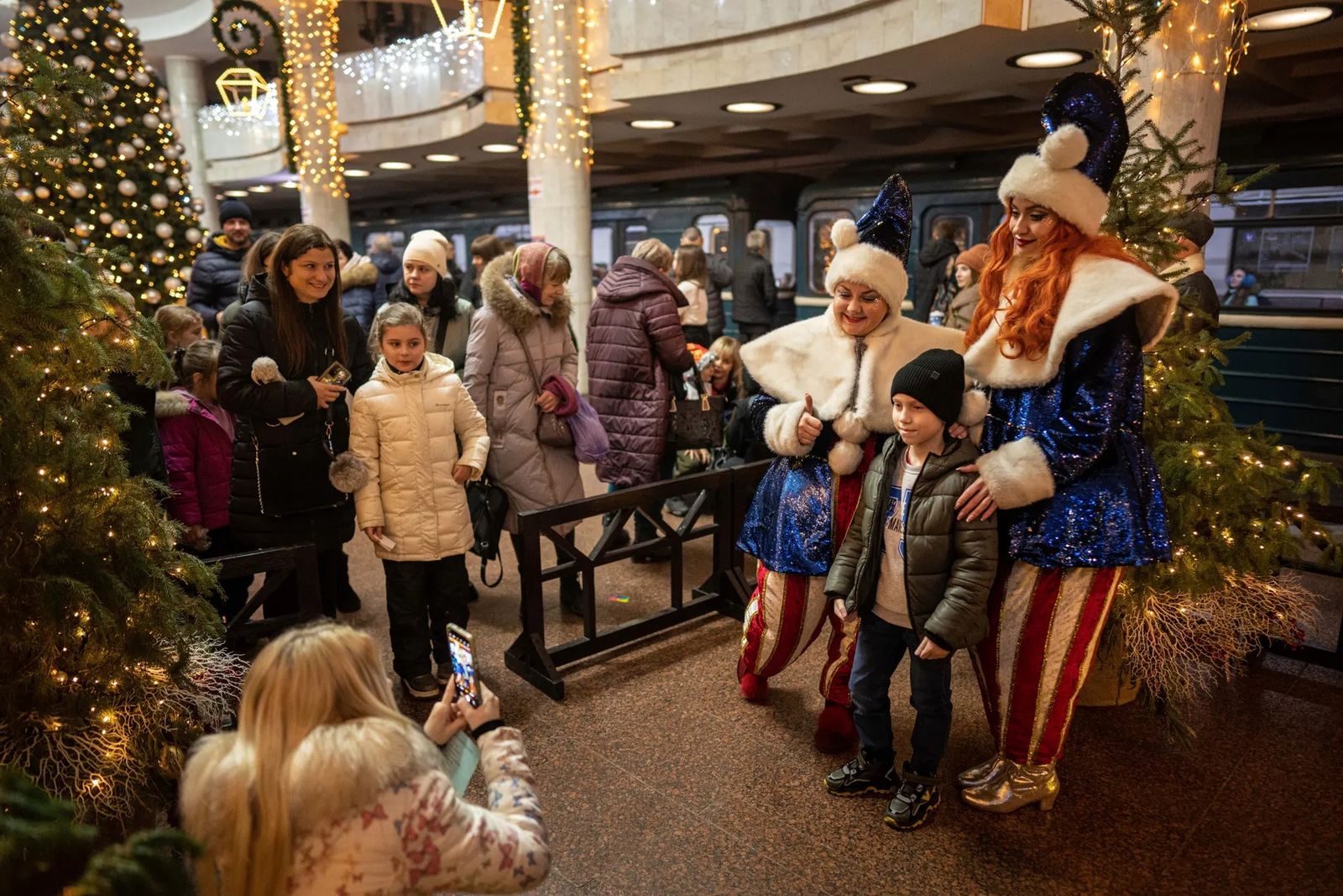 Мальчик фотографируется с наряженными в новогодние костюмы девушками на станции метро «Университет» в Харькове, украшенной к праздникам. 31 декабря / Evgeniy Maloletka / AP Photo / The Guardian
