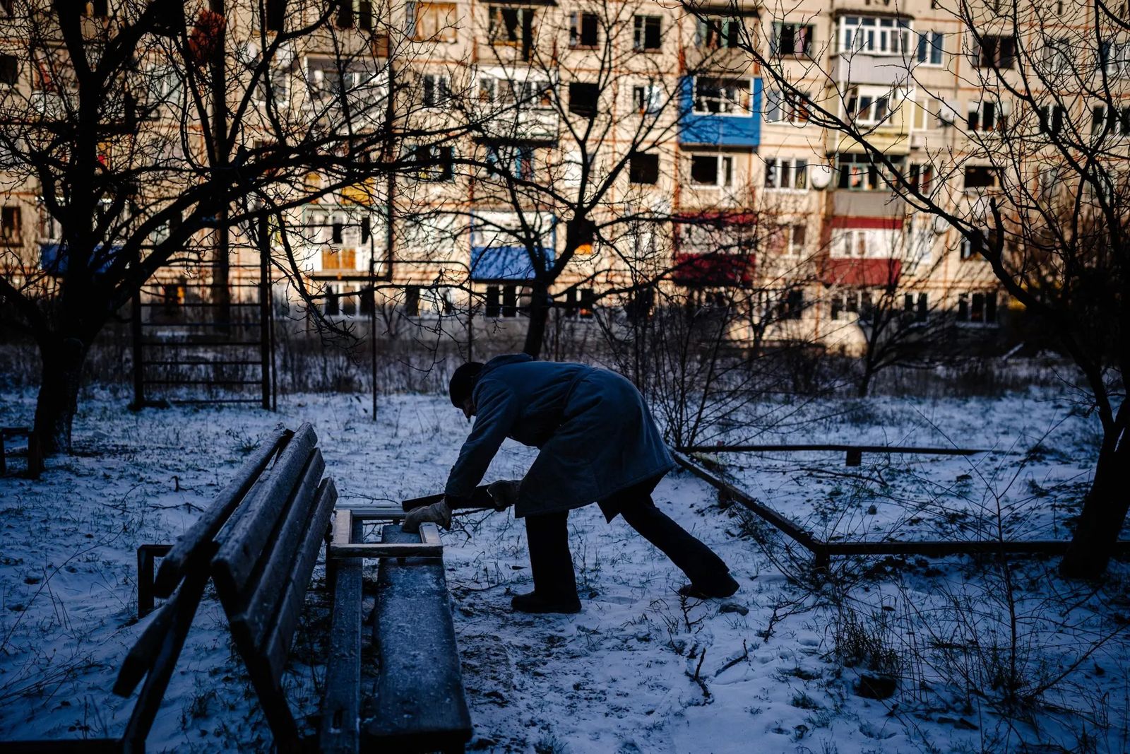 Житель украинского города Северска распиливает деревянную оконную раму, чтобы сжечь ее в печи, приготовить пищу и согреться. 8 января / Dimitar Dilkoff / AFP / Getty Images / The Guardian
