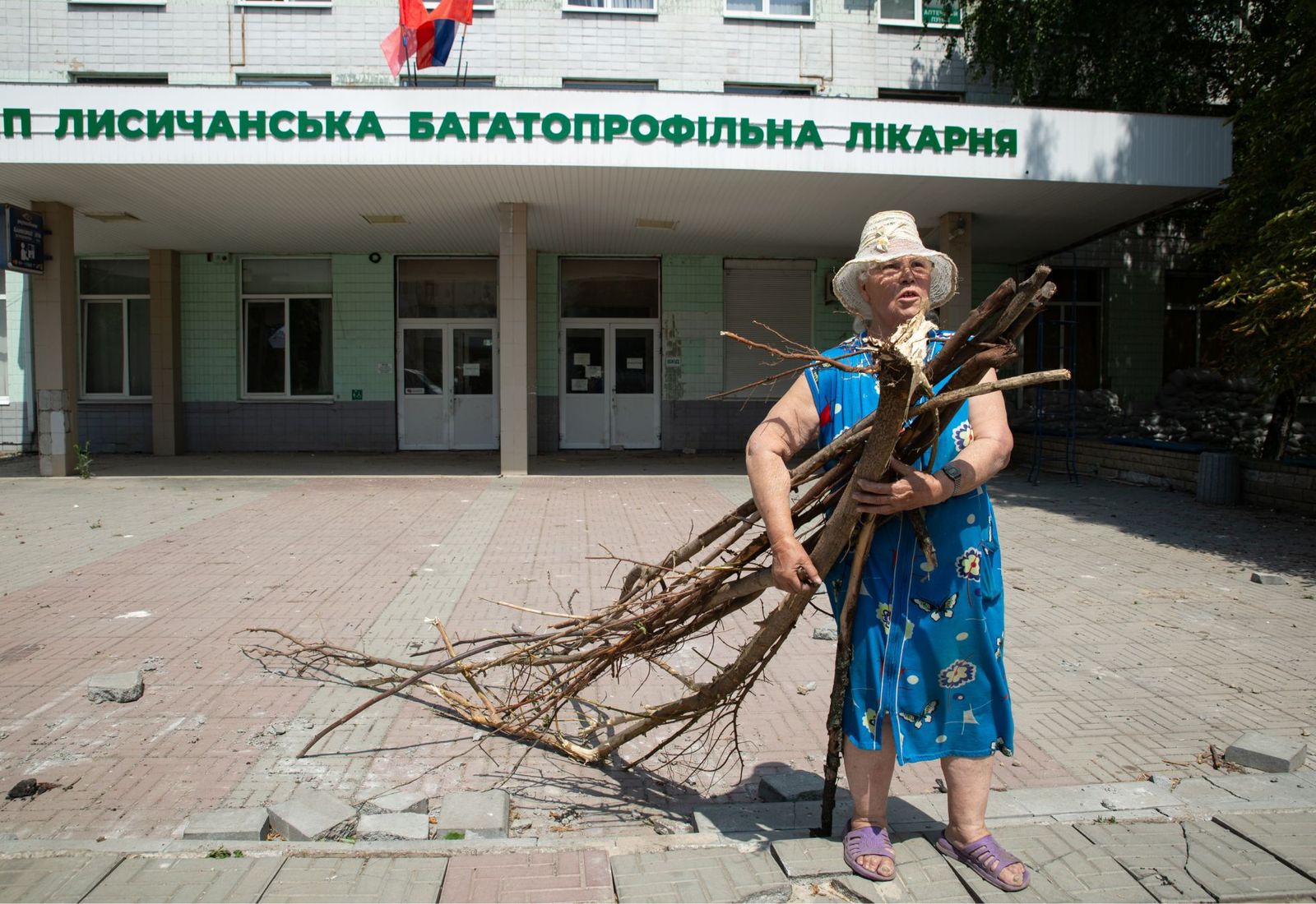 Женщина с охапкой дров у здания городской больницы в Лисичанске. Лисичанск был одним из последних городов Луганской области, который контролировали ВСУ. С конца апреля в городе отсутствовали газ, водо- и электроснабжение. 3 июля / Александр Река / ТА