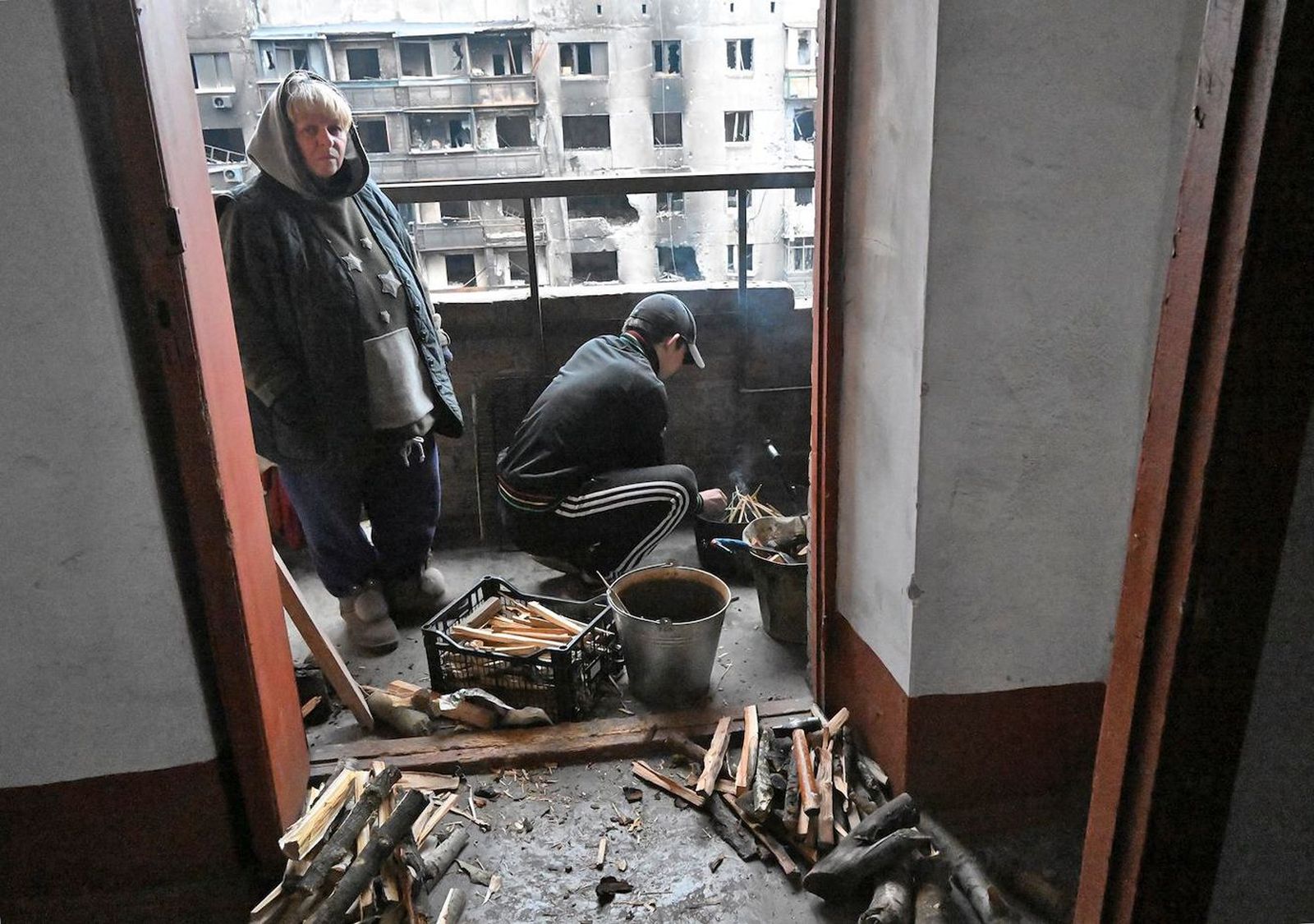 Жители Мариуполя разводят костер на балконе поврежденного жилого дома в Правобережном районе города. С конца февраля город находится в осаде без электричества, воды и отопления. 14 апреля / Анатолий Жданов / Коммерсантъ