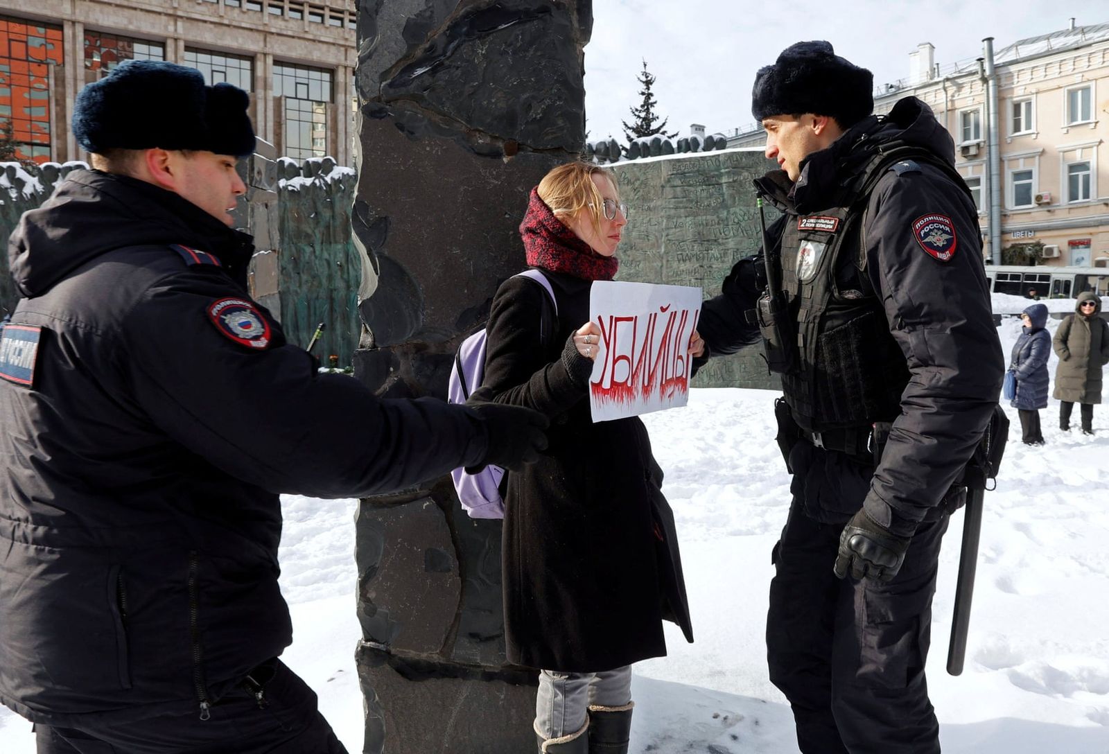Сотрудники полиции задерживают женщину, держащую плакат с надписью «убийцы» во время возложения цветов в память об Алексее Навальном у Стены скорби в Москве. 18 февраля / Reuters