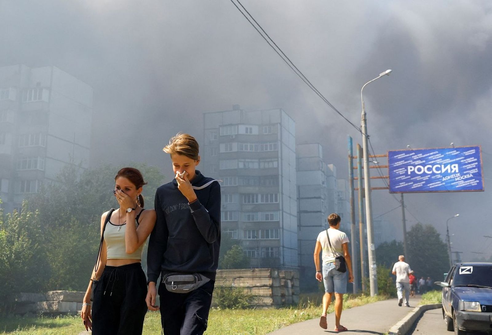Жители Донецка с прикрытыми органами дыхания проходят недалеко от торгового центра, загоревшегося в результате обстрела со стороны ВСУ, сообщает мэр Донецка‌. 24 августа / Alexander Ermochenko / Reuters / Scanpix / LETA / Meduza