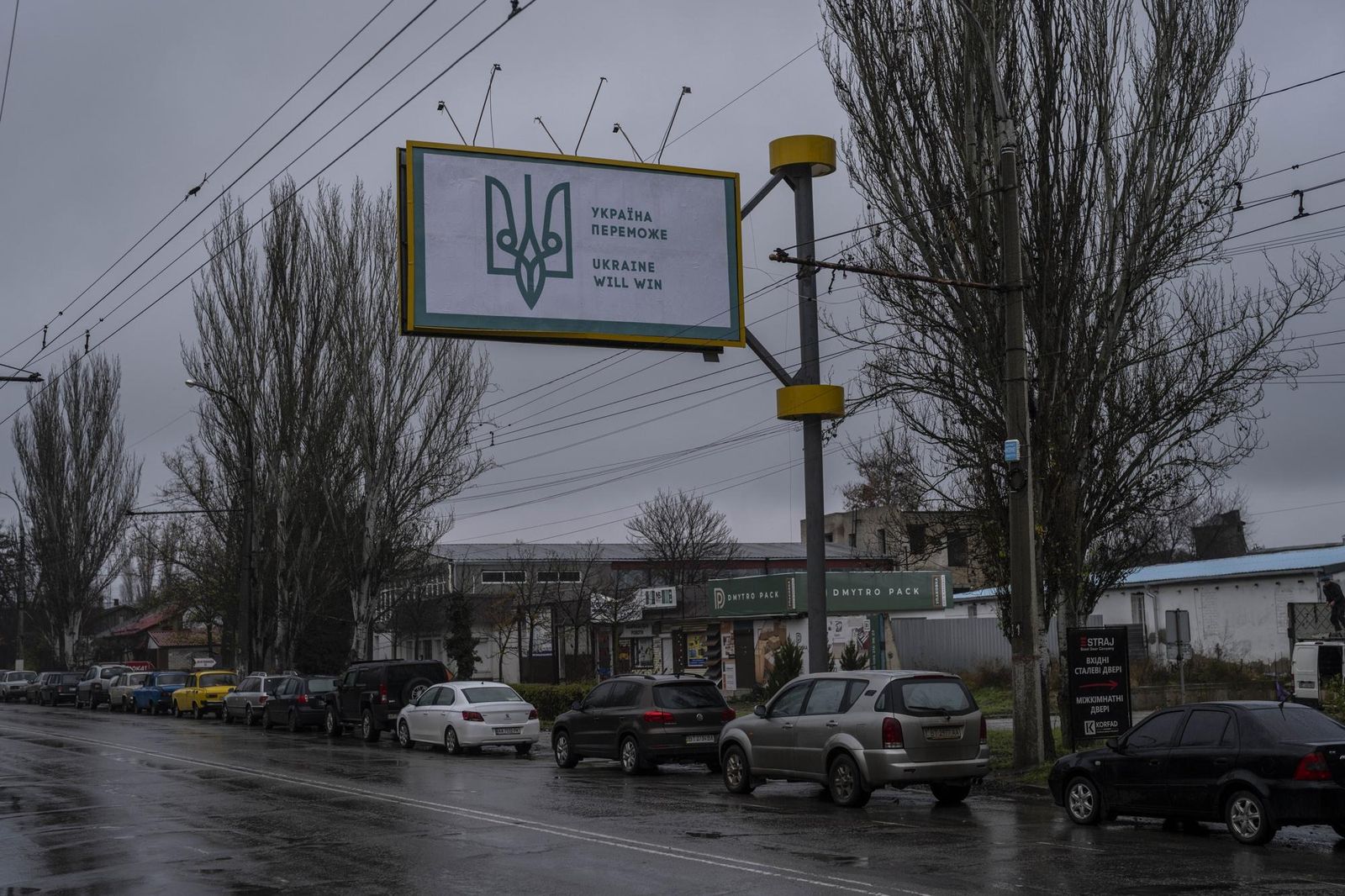 Автомобили выстраиваются в очередь на заправку под недавно установленным украинским рекламным щитом в Херсоне. Во время российской оккупации в городе размещались пропагандистские билборды с надписями «Россия здесь навсегда». 25 ноября / Bernat Armang