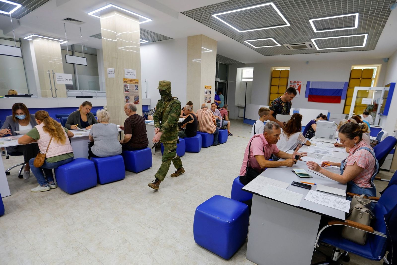 Военнослужащий пророссийских войск входит в здание МВД, пока местные жители подают документы на получение российского гражданства и паспорта в Херсоне. На оккупированных территориях Запорожской и Херсонской областях Украины российские паспорта стали 