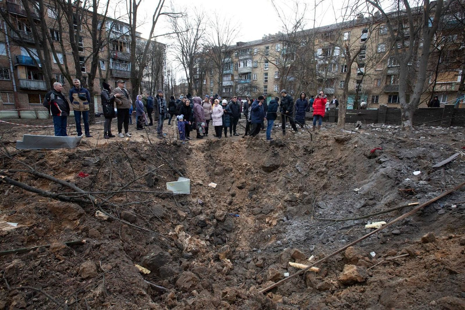 Жители Киева возле воронки, которая образовалась после попадания в землю российской ракеты во время массированного ракетного обстрела города в новогоднюю ночь​ Oleksii Chumachenko / Anadolu Agency / ABACAPRESS / ddp images / Vida Press / Meduza