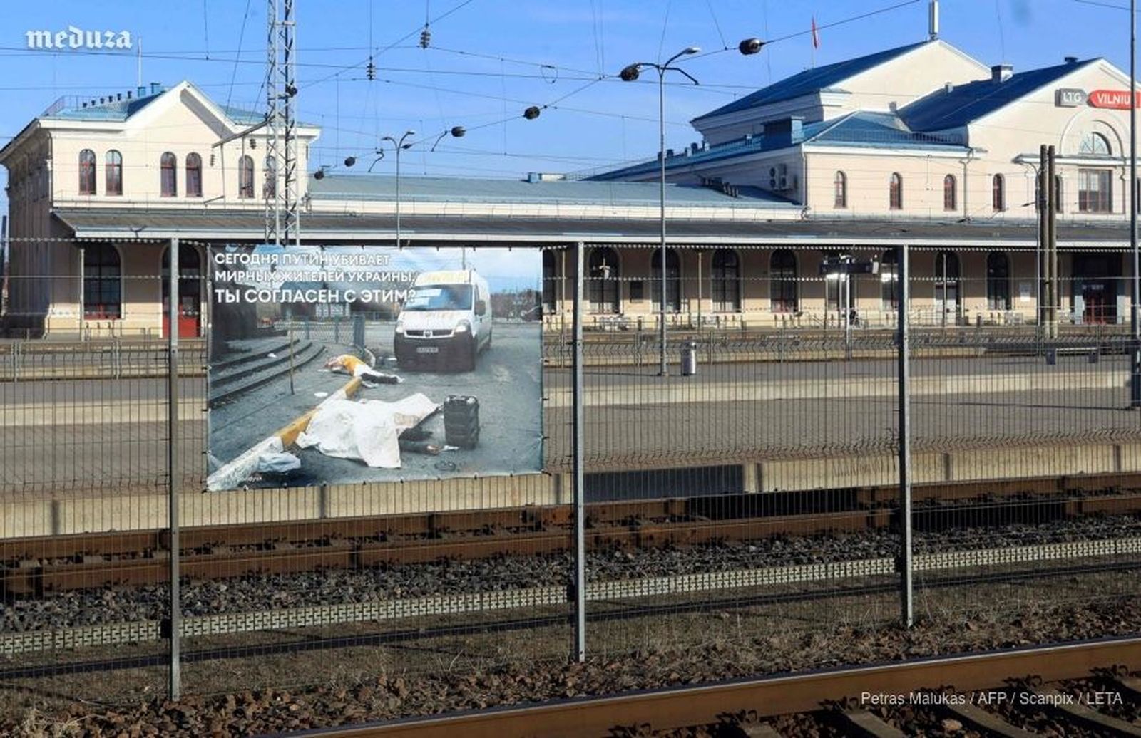 На путях вокзала Вильнюса вывешены фотографии войны в Украине. Так Литовская железная дорога решила привлечь внимание пассажиров проезжающего поезда Москва — Калининград. «Сегодня Путин убивает мирных жителей Украины. Вы согласны с этим?», — встречае