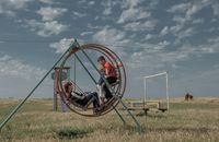 «Застывшая Кубань». Фотопроект о магическом реализме южного края, Дети качаются на качелях посреди заросшего поля на окраине поселка Приазовского — миниатюра