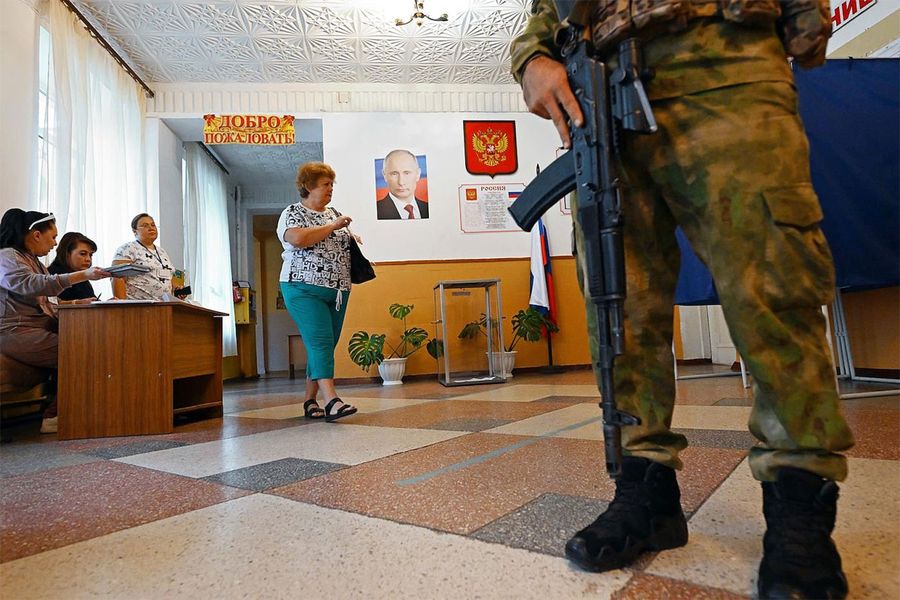 Жители Донецкой области пришли на выборы в органы местного самоуправления, где их встречают люди с автоматами. 8 сентября / Anatoly Zhdanov / Kommersant / The Moscow Times / Фотохроника войны. Главные кадры сентября: День знаний в убежищах, выборы под автоматами и визит Ким Чен Ына в Россию — Discours.io