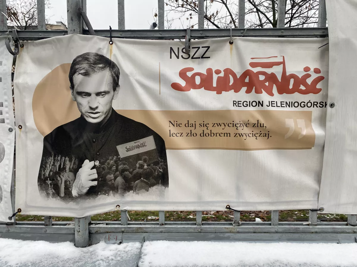 Баннер с изображением Ежи Попелушко установленный на территории церкви в Варшаве, где он служил и похоронен. Надпись на польском «Не будь побежден злом, но побеждай зло добром». Фото автора